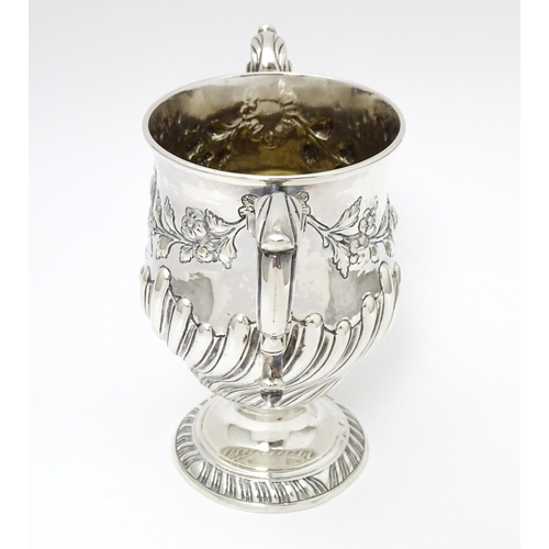 409 - A 19thC Irish silver twin handled pedestal cup with fluted body, and embossed floral and foliate swa... 