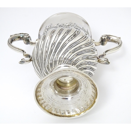 409 - A 19thC Irish silver twin handled pedestal cup with fluted body, and embossed floral and foliate swa... 