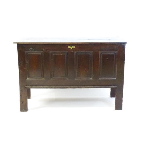 1337 - An early 18thC oak coffer with a removeable lid above a panelled front and sides raised on four tall... 