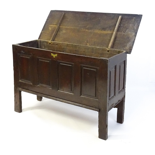 1337 - An early 18thC oak coffer with a removeable lid above a panelled front and sides raised on four tall... 