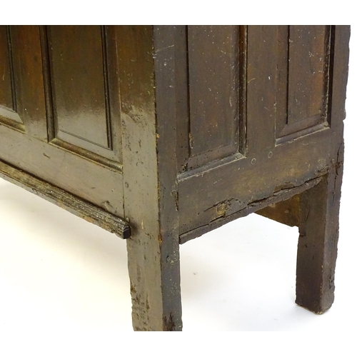 1337 - An early 18thC oak coffer with a removeable lid above a panelled front and sides raised on four tall... 