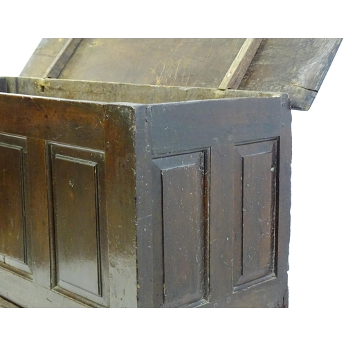 1337 - An early 18thC oak coffer with a removeable lid above a panelled front and sides raised on four tall... 