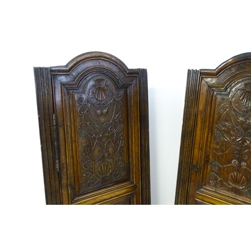 1339 - A pair of 19thC carved oak cupboards with rounded tops, panelled doors, fluted pilasters and having ... 