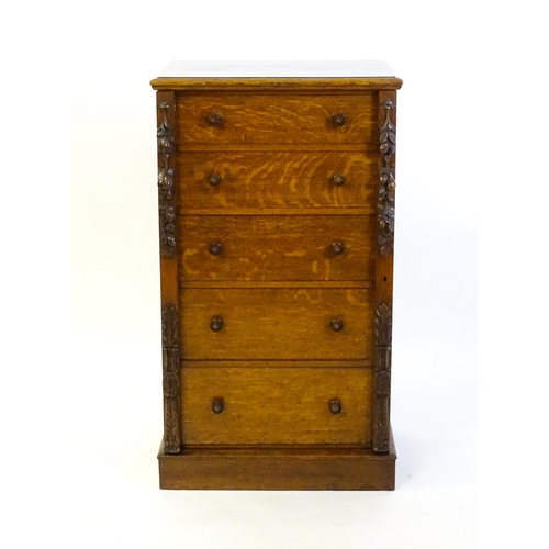 1346 - A Victorian oak Wellington chest, with a moulded top above five graduated drawers with stylised acor... 