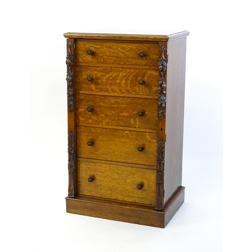 1346 - A Victorian oak Wellington chest, with a moulded top above five graduated drawers with stylised acor... 