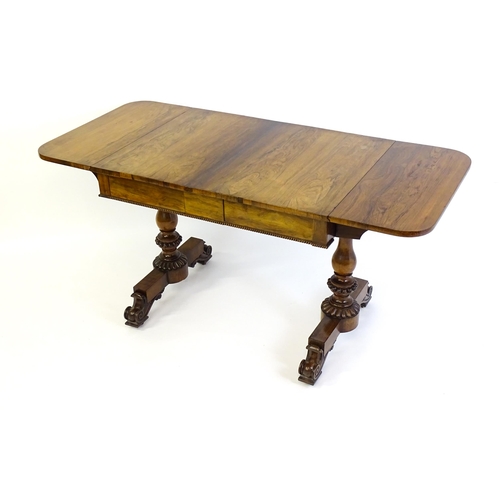 1358 - An early / mid 19thC rosewood sofa table, with drop flaps to either side and two frieze drawers with... 