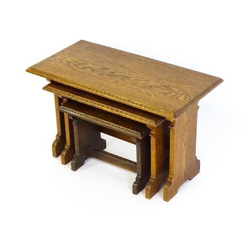 1359 - An oak Cotswold school nest of tables with carved edges, shaped supports and H - stretchers. 28