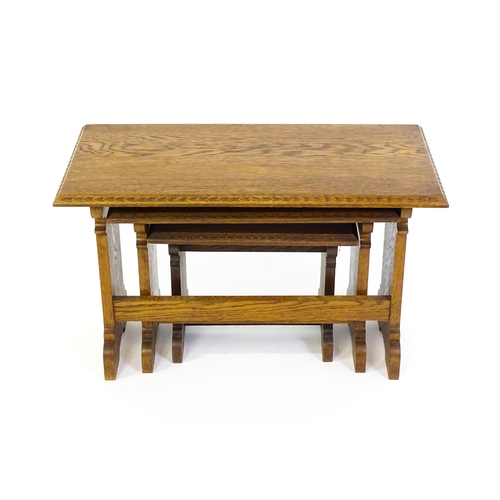 1359 - An oak Cotswold school nest of tables with carved edges, shaped supports and H - stretchers. 28