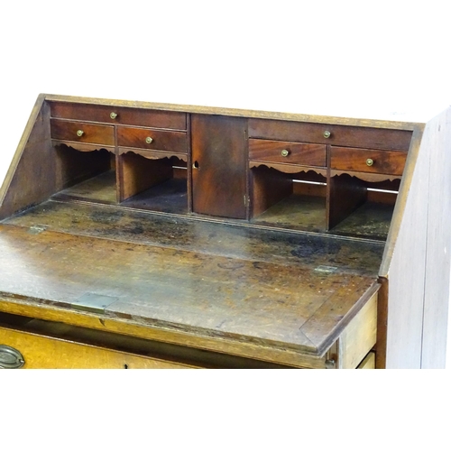 1372 - An 18thC oak bureau with a crossbanded fall front containing a fitted interior with small drawers, c... 