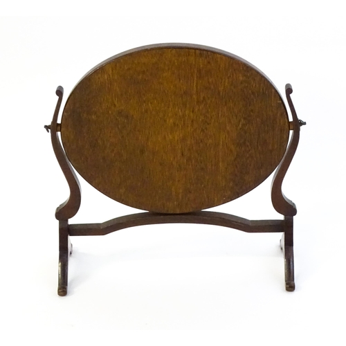 1375 - An early 20thC mahogany skeleton mirror / toilet mirror with an oval surround raised on shaped suppo... 