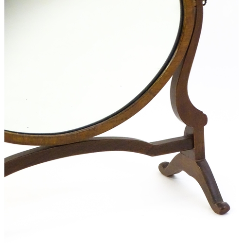 1375 - An early 20thC mahogany skeleton mirror / toilet mirror with an oval surround raised on shaped suppo... 