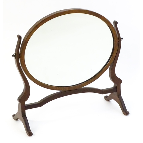 1375 - An early 20thC mahogany skeleton mirror / toilet mirror with an oval surround raised on shaped suppo... 