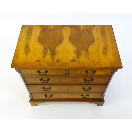 1384 - A yew wood veneered chest of drawers, with a rectangular crossbanded top above two short over three ... 