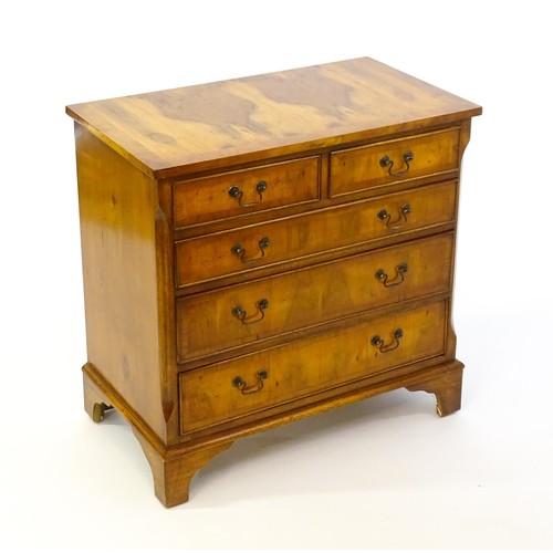 1384 - A yew wood veneered chest of drawers, with a rectangular crossbanded top above two short over three ... 