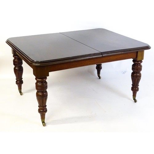 1391 - An early 20thC mahogany extending dining table, with a moulded top above four turned tapering legs w... 