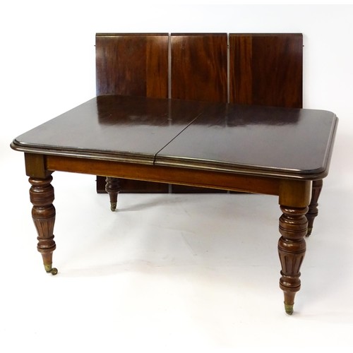 1391 - An early 20thC mahogany extending dining table, with a moulded top above four turned tapering legs w... 