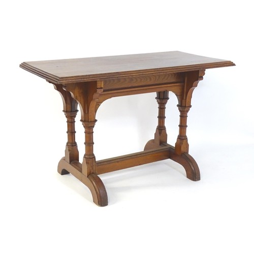 1398 - A late 19thC pine Gothic centre table, with a rectangular moulded top above four column formed taper... 