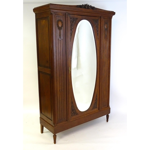 1417 - A late 19thC continental walnut armoire, with a carved floral pediment above a large mirrored door f... 