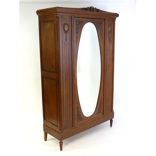 1417 - A late 19thC continental walnut armoire, with a carved floral pediment above a large mirrored door f... 