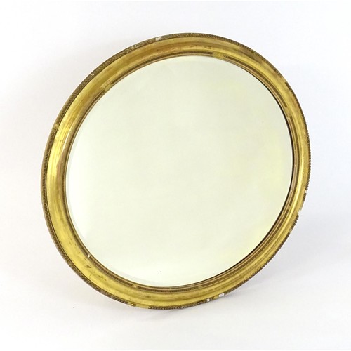 1418 - A 19thC oval giltwood and gesso wall mirror with bevelled glass. The surround having moulded and bea... 