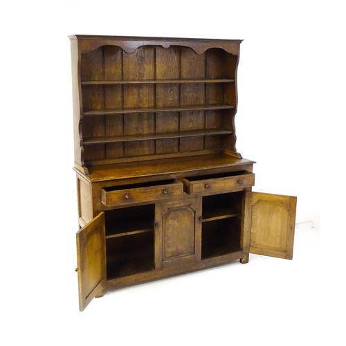 1420 - A 20thC oak dresser with a shaped three tier plate rack, the base comprising two short drawers over ... 