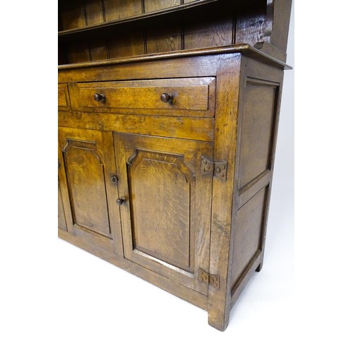 1420 - A 20thC oak dresser with a shaped three tier plate rack, the base comprising two short drawers over ... 