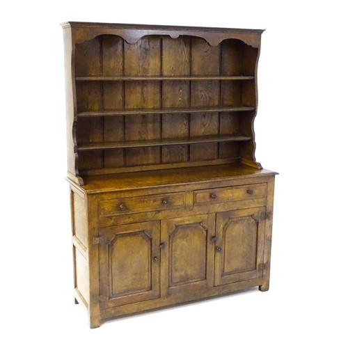 1420 - A 20thC oak dresser with a shaped three tier plate rack, the base comprising two short drawers over ... 