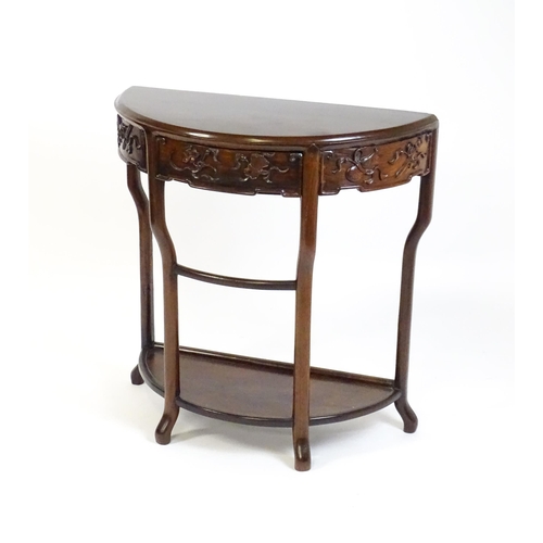 1422 - A late 19thC / early 20thC Qing dynasty demi lune table, with a carved front, a frieze drawer and ra... 