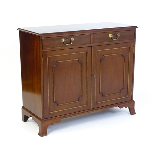 1423 - A mahogany cabinet with a moulded top above two short drawers and two panelled cupboard, the cabinet... 