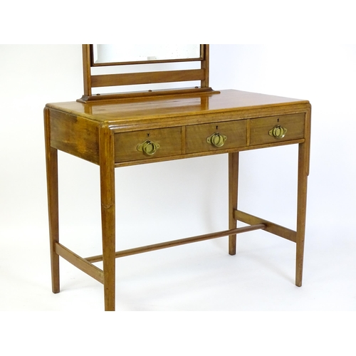 1430 - A mid 20thC Art Deco walnut dressing table, with a squared mirror above three short drawers with bra... 