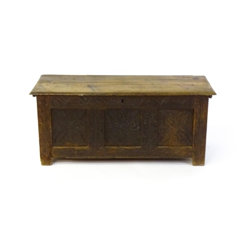 1432 - A 17thC oak coffer with a hinged lid above a carved, panelled front. The lid opening to show two fit... 