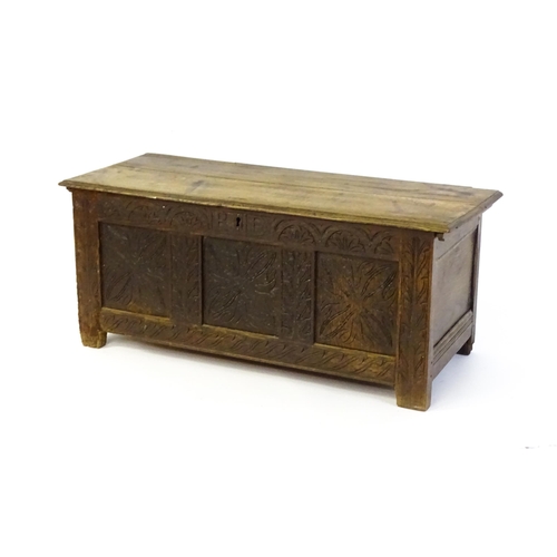 1432 - A 17thC oak coffer with a hinged lid above a carved, panelled front. The lid opening to show two fit... 