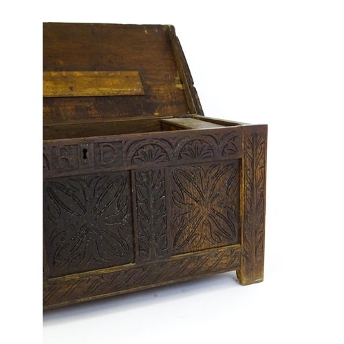 1432 - A 17thC oak coffer with a hinged lid above a carved, panelled front. The lid opening to show two fit... 