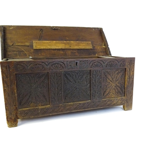 1432 - A 17thC oak coffer with a hinged lid above a carved, panelled front. The lid opening to show two fit... 