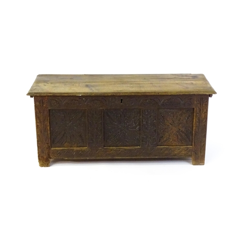 1432 - A 17thC oak coffer with a hinged lid above a carved, panelled front. The lid opening to show two fit... 