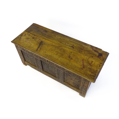 1432 - A 17thC oak coffer with a hinged lid above a carved, panelled front. The lid opening to show two fit... 