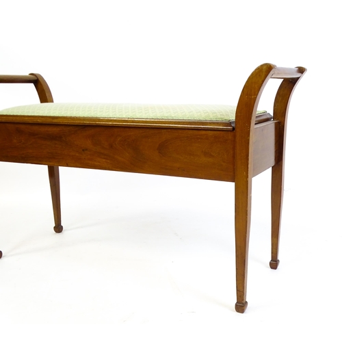 1459 - An early 20thC mahogany piano stool flanked by carrying handles with an upholstered, hinged seat abo... 