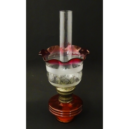 1314 - An early 20thC table oil lamp, the cranberry glass reservoir supporting a brass burner (marked 'Popu... 