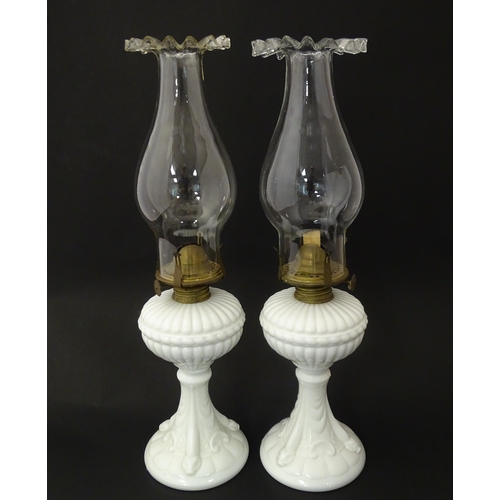 1315 - A pair of 19thC table oil lamps, the milk glass column bases with integral reservoirs, decorated wit... 