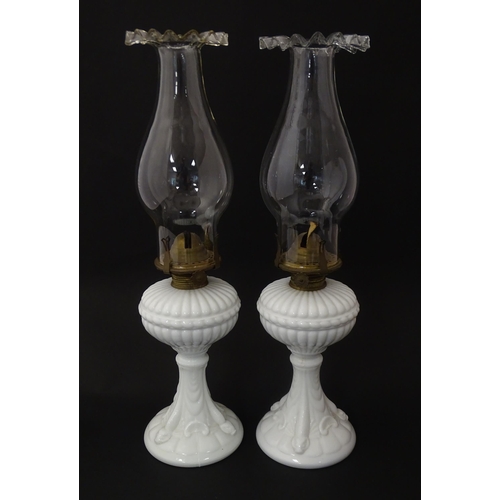 1315 - A pair of 19thC table oil lamps, the milk glass column bases with integral reservoirs, decorated wit... 