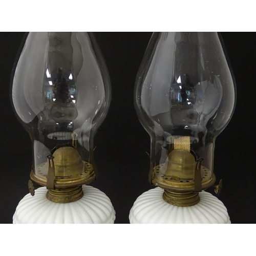 1315 - A pair of 19thC table oil lamps, the milk glass column bases with integral reservoirs, decorated wit... 