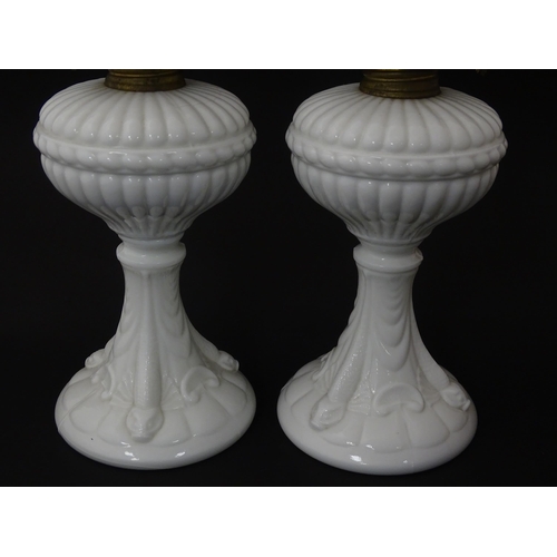 1315 - A pair of 19thC table oil lamps, the milk glass column bases with integral reservoirs, decorated wit... 