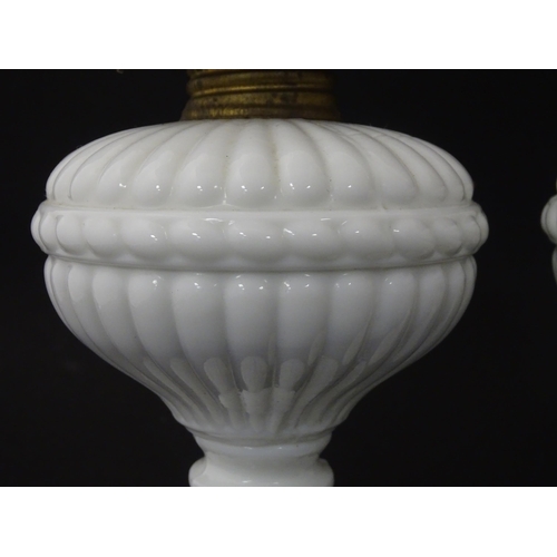 1315 - A pair of 19thC table oil lamps, the milk glass column bases with integral reservoirs, decorated wit... 