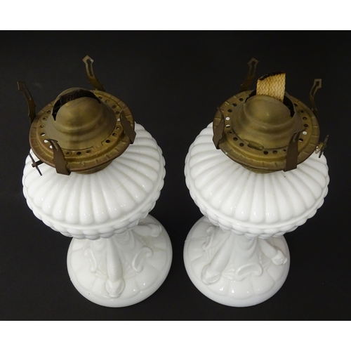 1315 - A pair of 19thC table oil lamps, the milk glass column bases with integral reservoirs, decorated wit... 