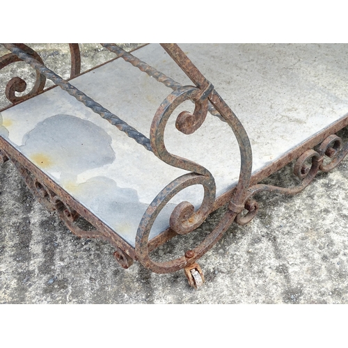 1323 - A mid 20thC wrought iron garden / patio table, the scrolled frame supporting two inset stone tiers, ... 