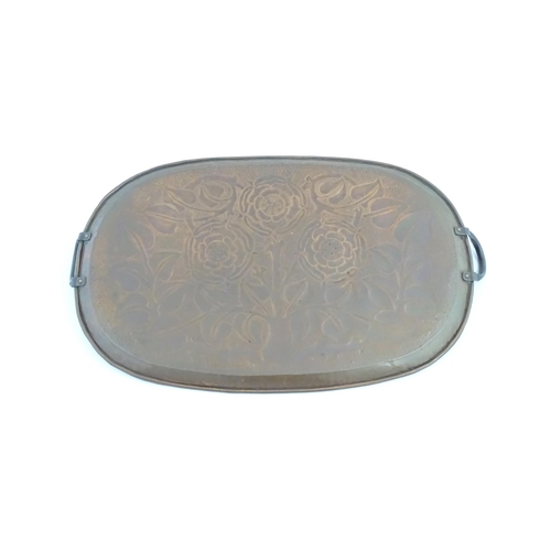 1011 - An Arts and Crafts style copper tray of oval form with twin handles and hammered and punchwork detai... 