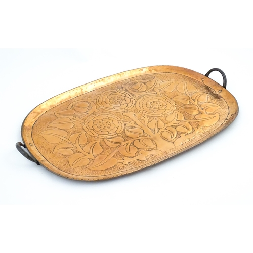 1011 - An Arts and Crafts style copper tray of oval form with twin handles and hammered and punchwork detai... 