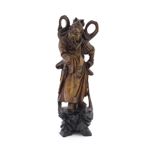 1024 - A Chinese carved wooden model of a standing figure with a sword. Approx. 16