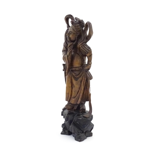 1024 - A Chinese carved wooden model of a standing figure with a sword. Approx. 16