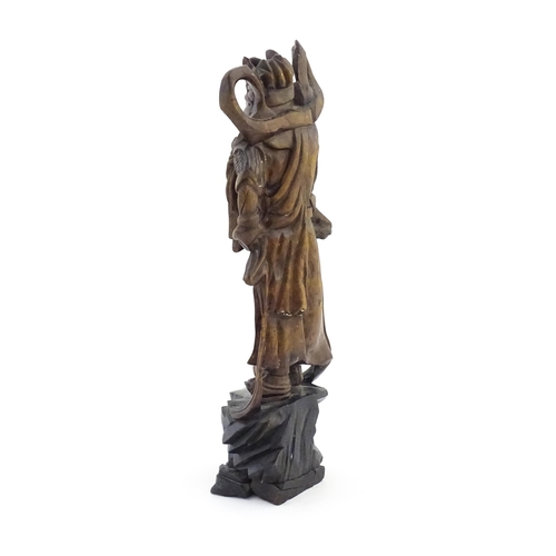 1024 - A Chinese carved wooden model of a standing figure with a sword. Approx. 16